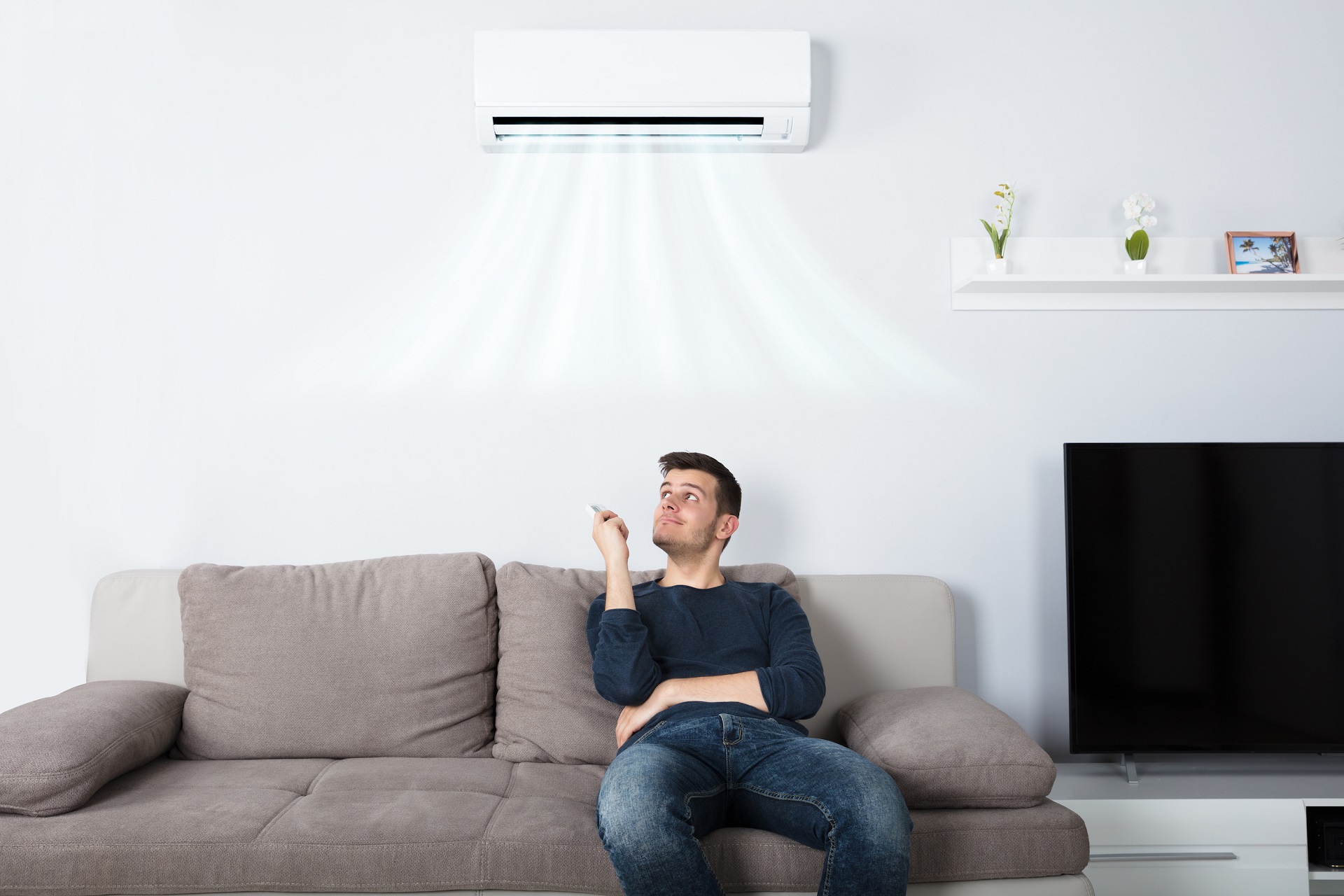 Man operating air conditioner at home